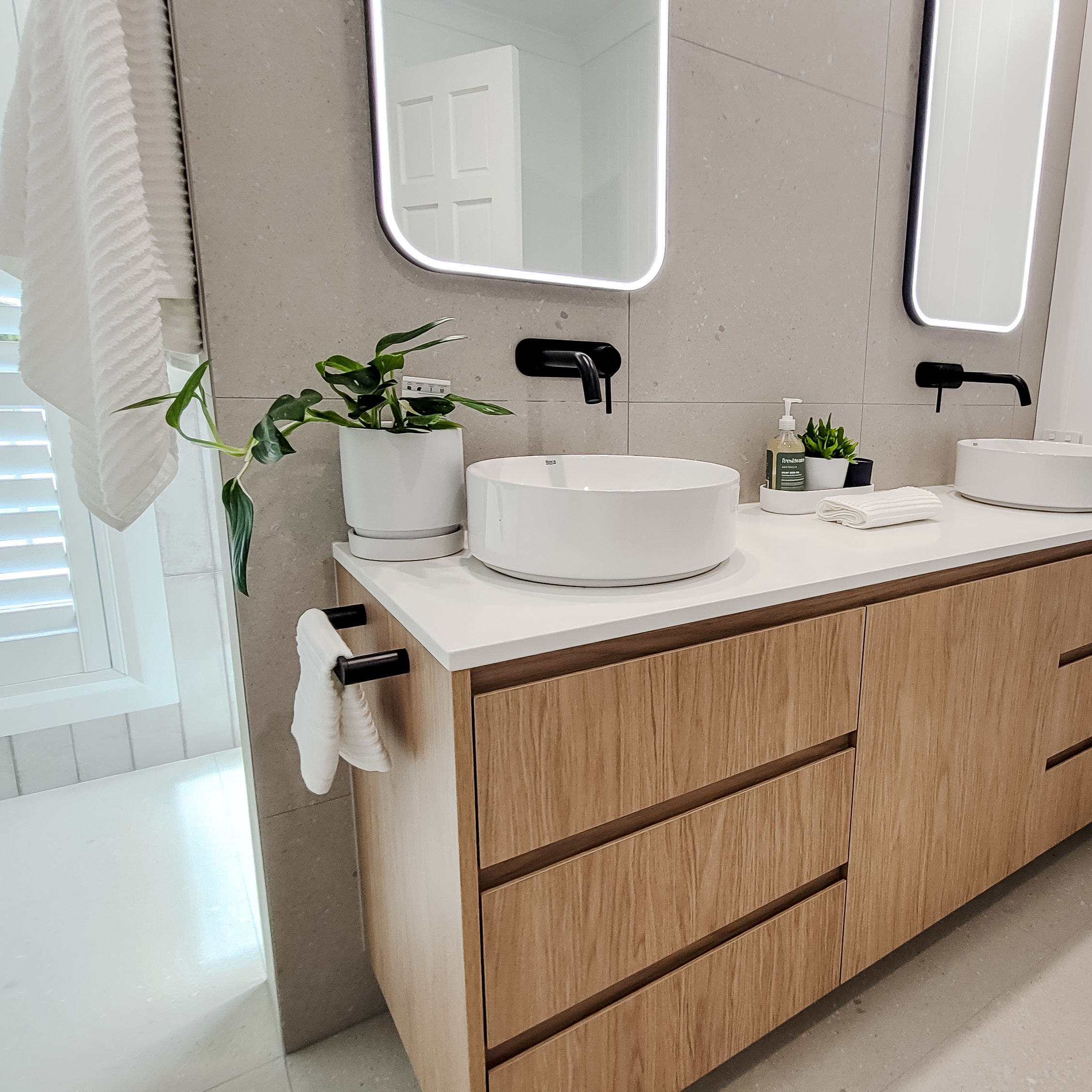 Double vanity with oak joinery and stone-look wall tiles