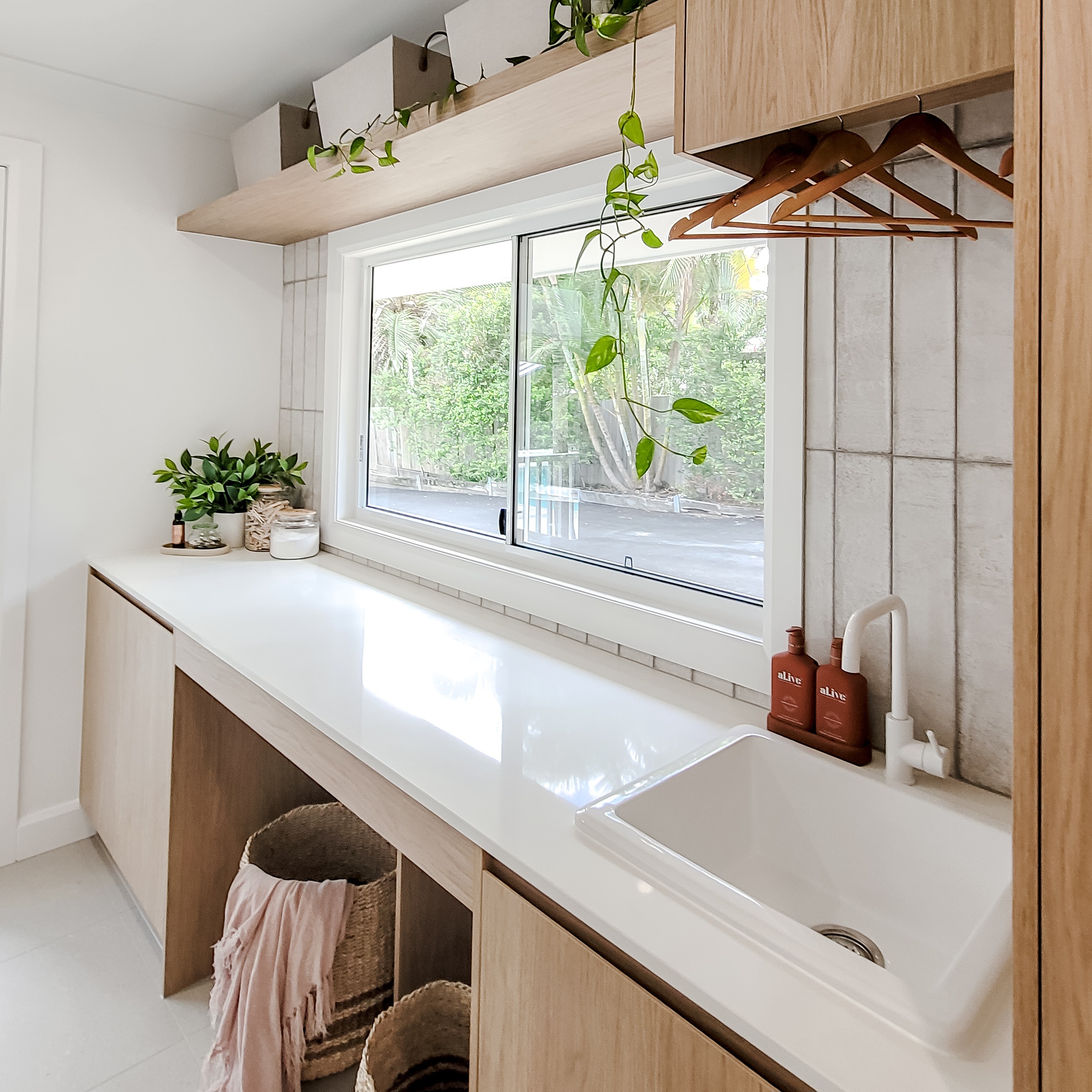 Bright laundry with subway splashback and oak cabinetry